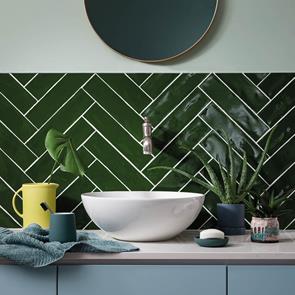 half tiled bathroom wall with herringbone indigio green poitiers tiles, with wall mounted tap and freestanding sink.